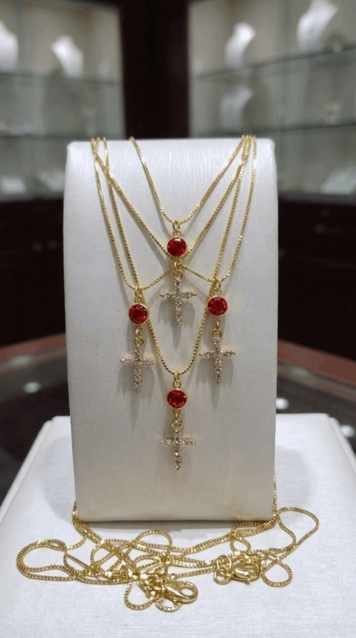 Gold-tone cross necklace with dangling red-orange and clear gemstone accents