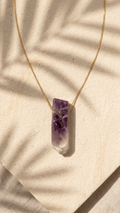 Gold necklace with small purple amethyst bar pendant and pale clear crystal base