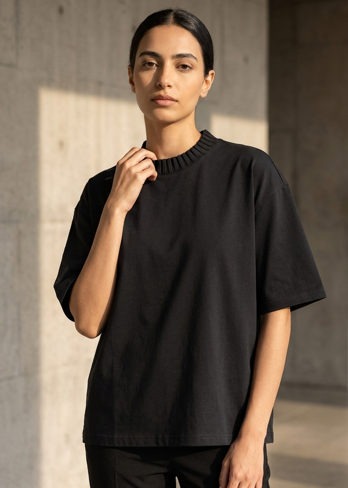 Black heavyweight knitted crew-neck T-shirt, model wearing it with short sleeves.