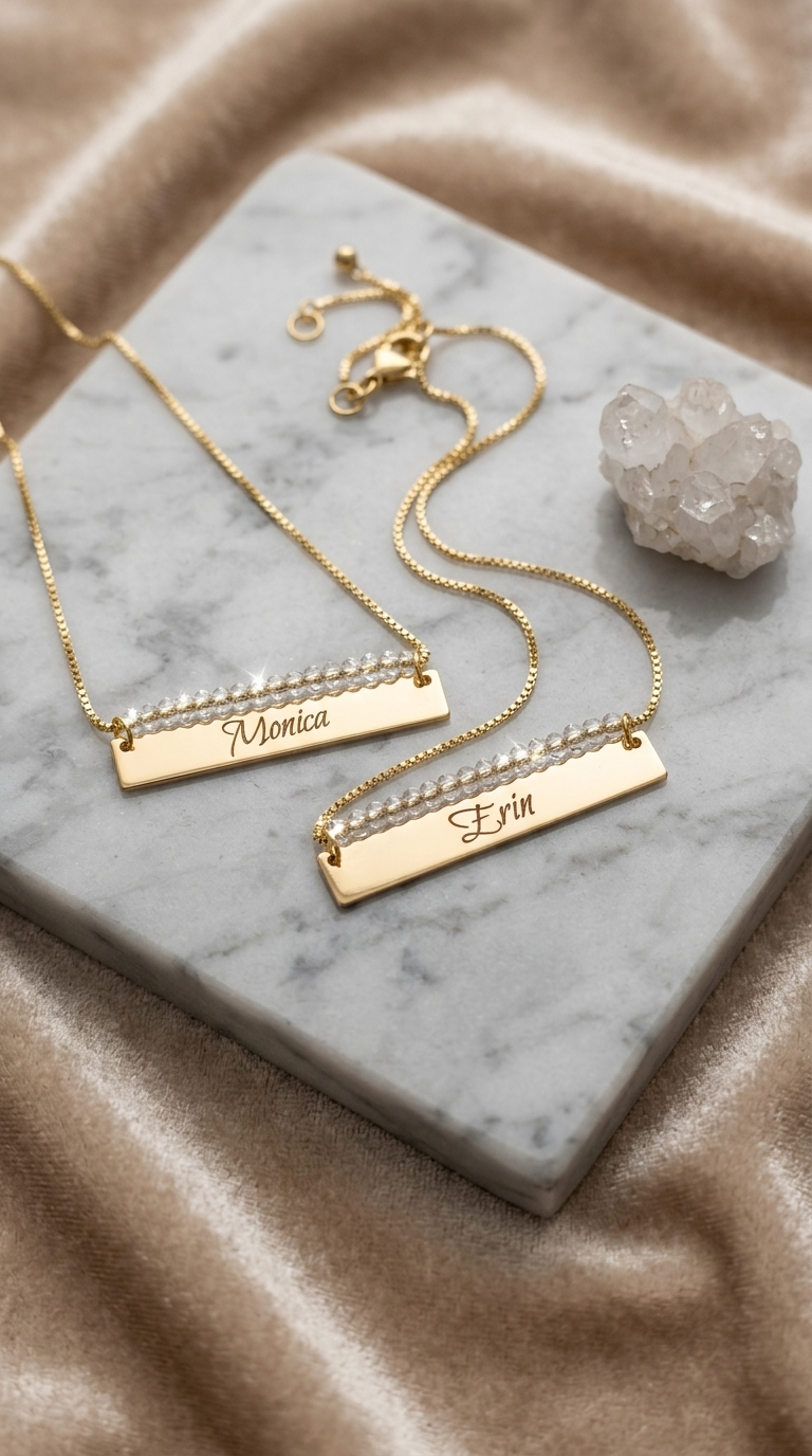 Gold beaded bar name necklace with engraved rectangular bar and heart-shaped clasp detail