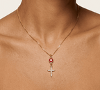 Gold cross necklace with red oval stone and white zircon details on pendant